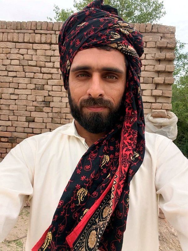 Afzaal, Script Writer at VillageWishes, holding a handwritten script board
